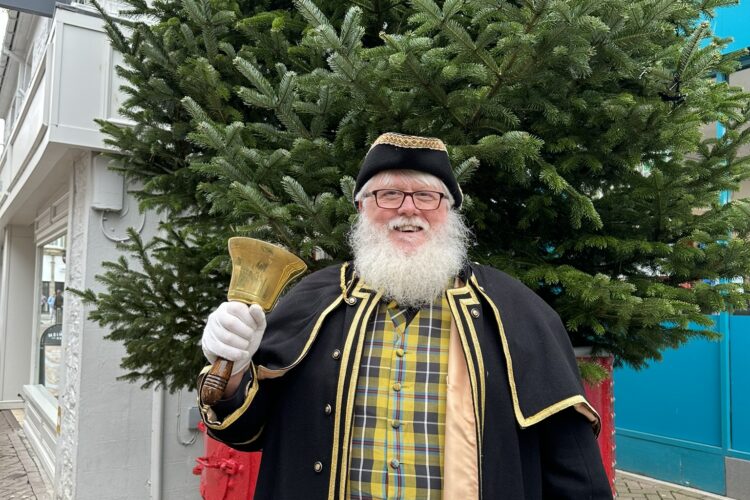 Image of the previous Newquay Town Crier in his regalia in front of a Christmas tree in Newquay Town Centre.